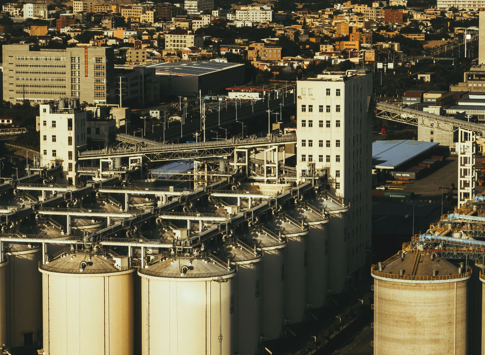 Processing plant and shipping containers beside a city, library photograph